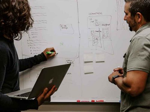 woman and man make notes on the blackboard